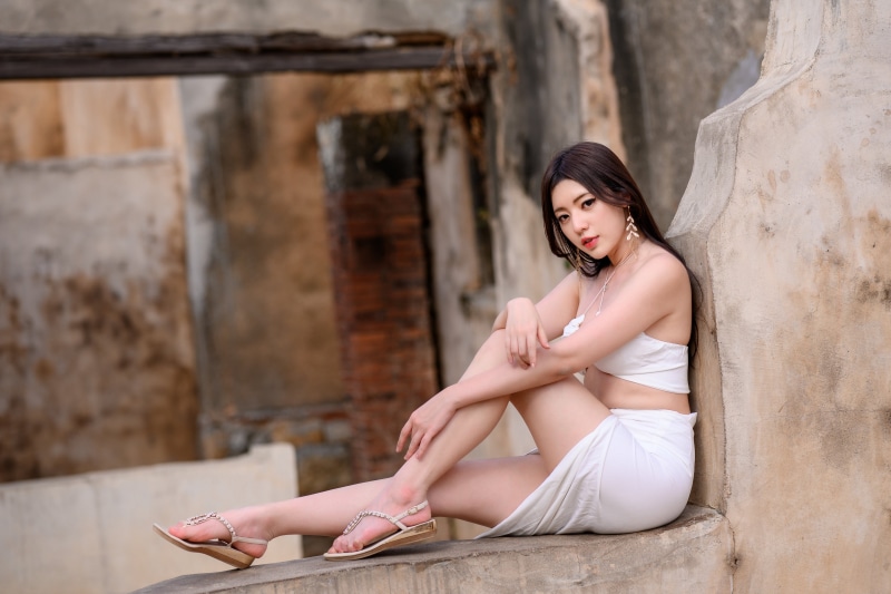 Asian woman sitting in white singlet and skirt