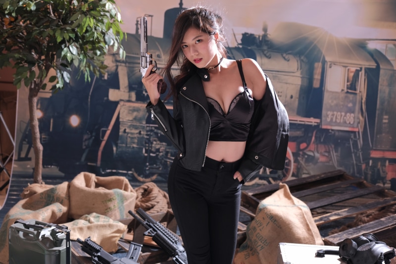 Asian woman in jacket holding pistol