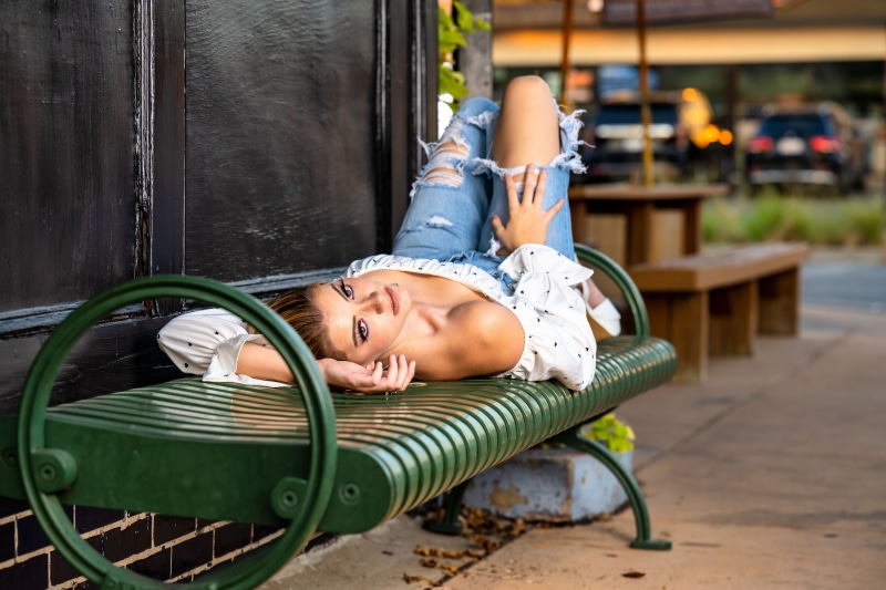 Woman in ripped jeans lying on a bench