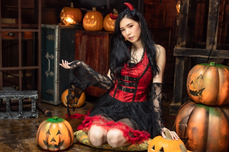 Asian girl in devil costume with pumpkins
