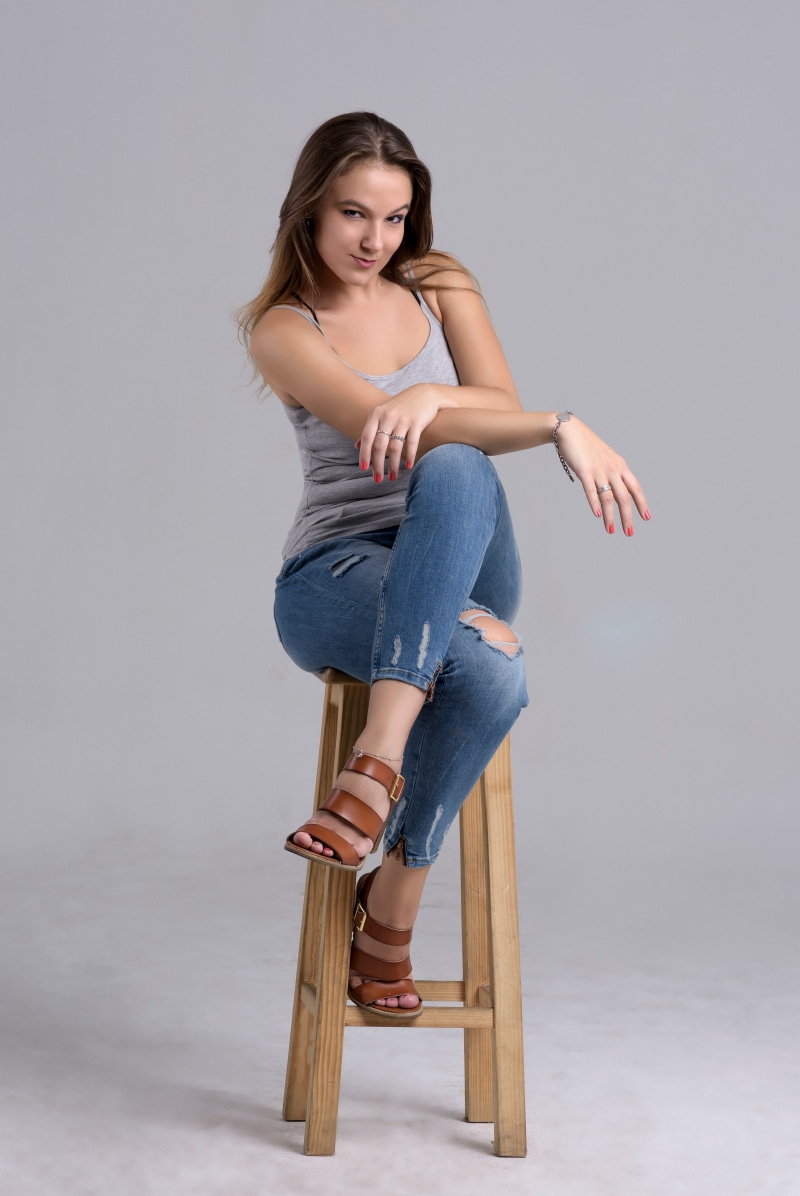 Woman in jeans and singlet sitting on a stool