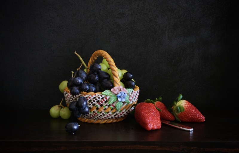 Still-life with strawberries and grapes in a wicker basket