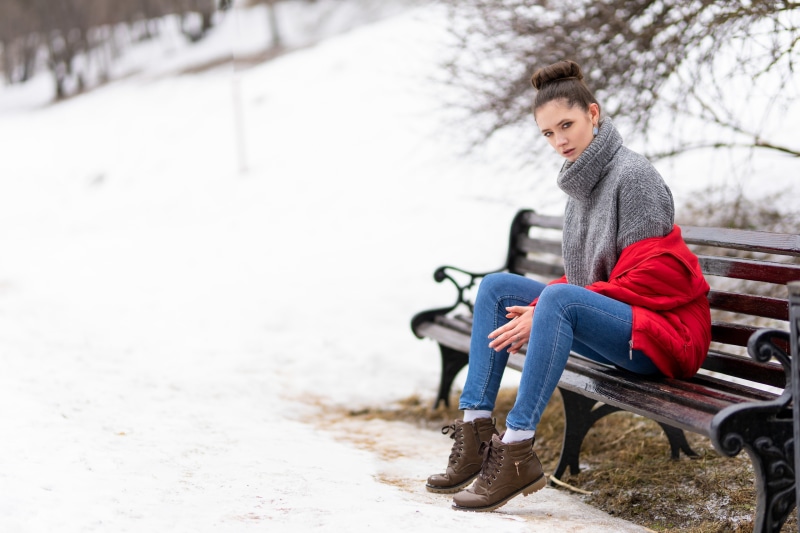 Woman in winter clothes sitting on a park bench