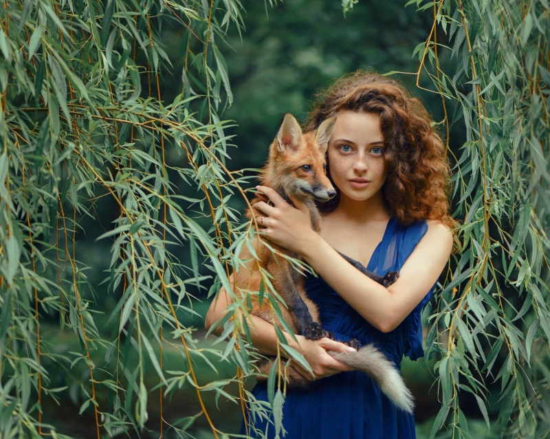 Young woman with curly hair holding a fox