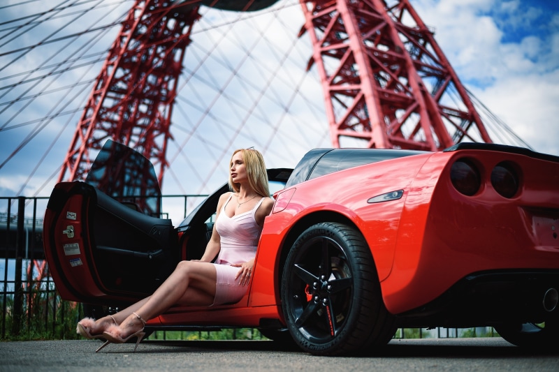 Blonde woman in pink dress sitting in red Corvette