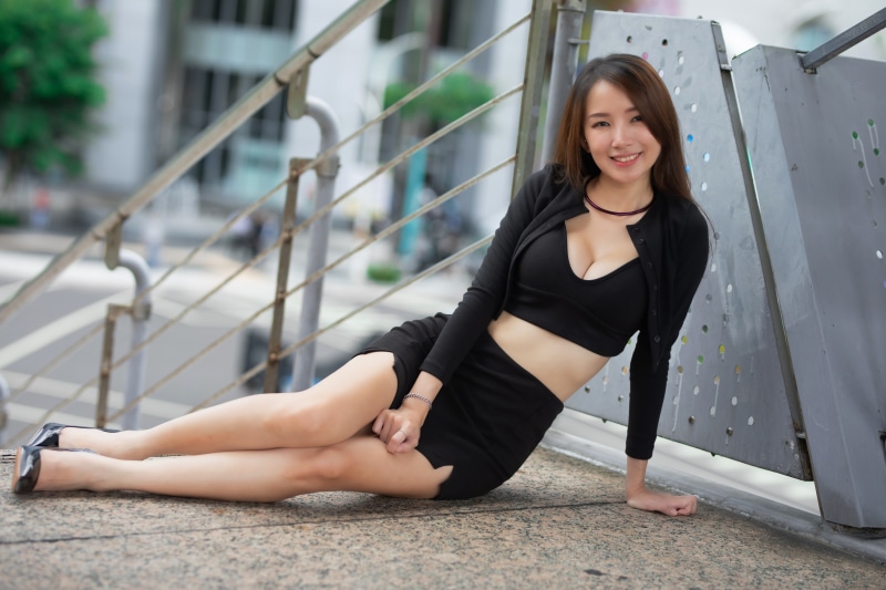 Asian woman in black skirt and top sitting