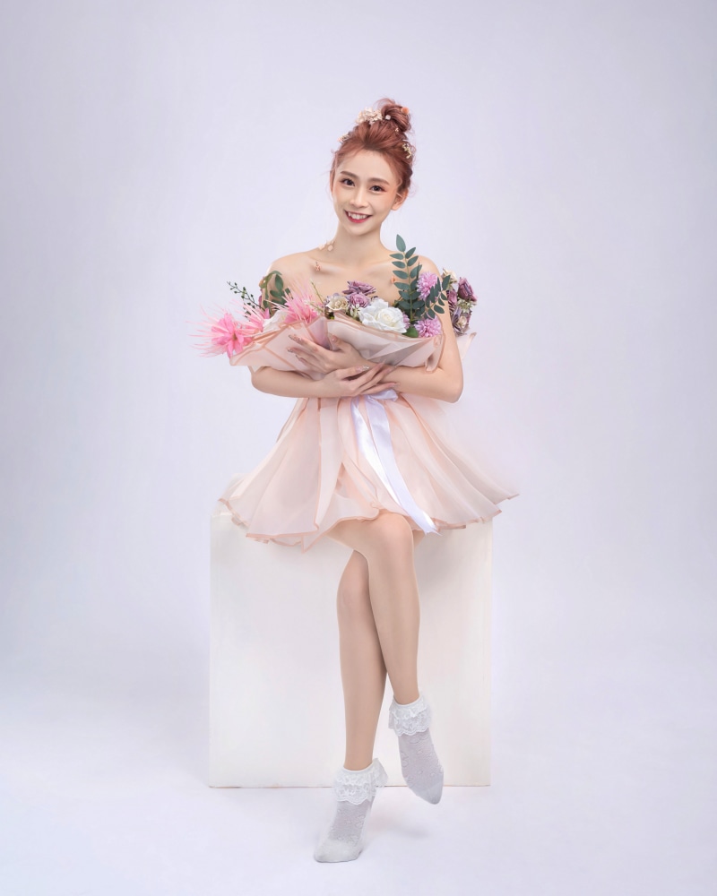 Asian woman in pink dress holding flowers
