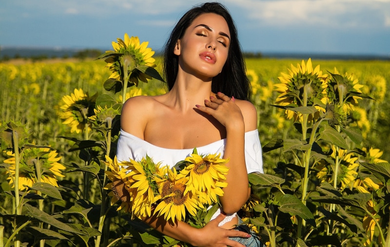 Brunette woman holding sunflowers in a field