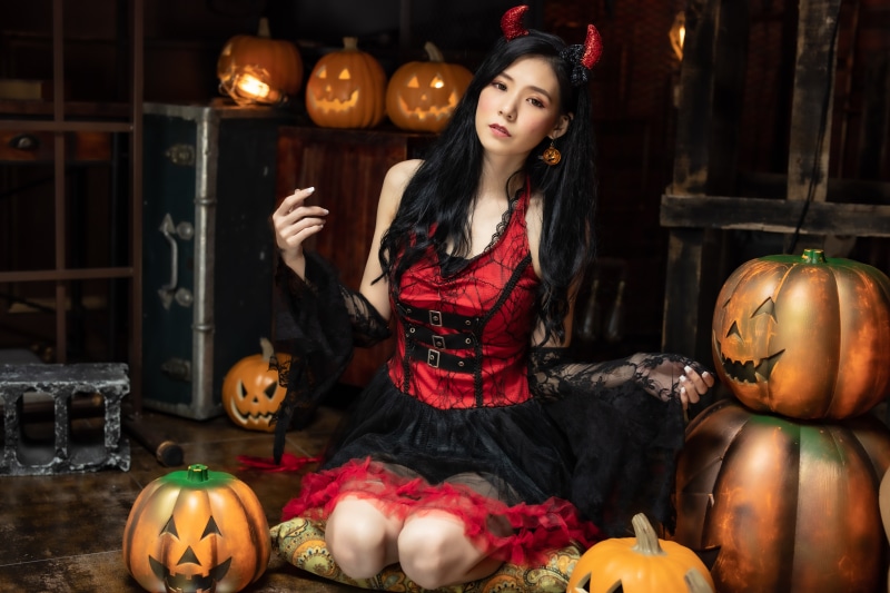 Asian woman in devil costume with pumpkins