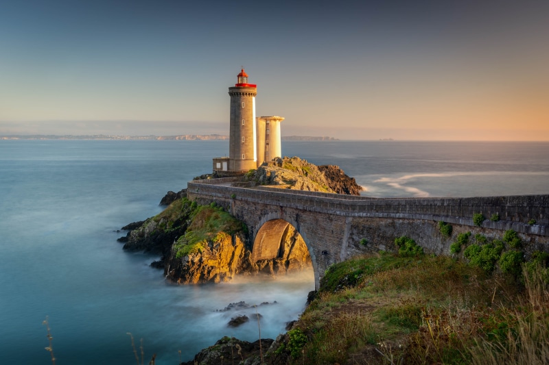 Lighthouse on a rocky island connected by a bridge, Brittany, France