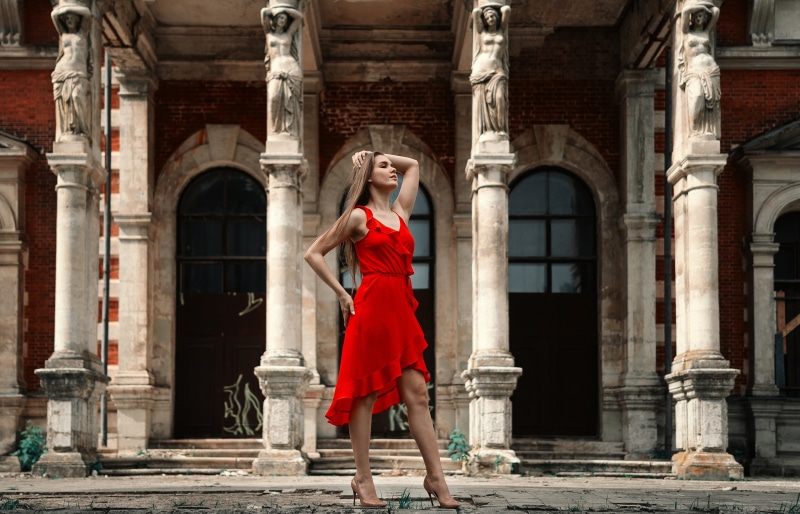 Woman in red dress posing near columns