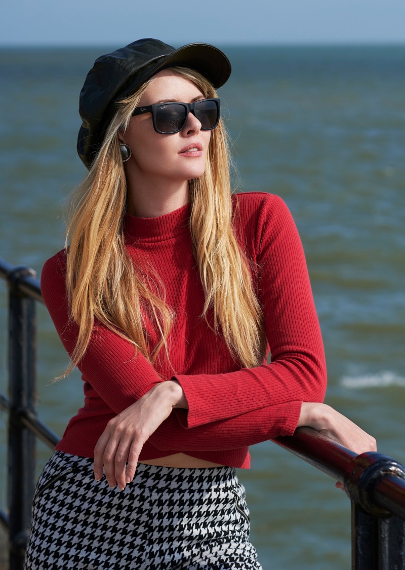 Blonde woman wearing a red sweater and houndstooth skirt