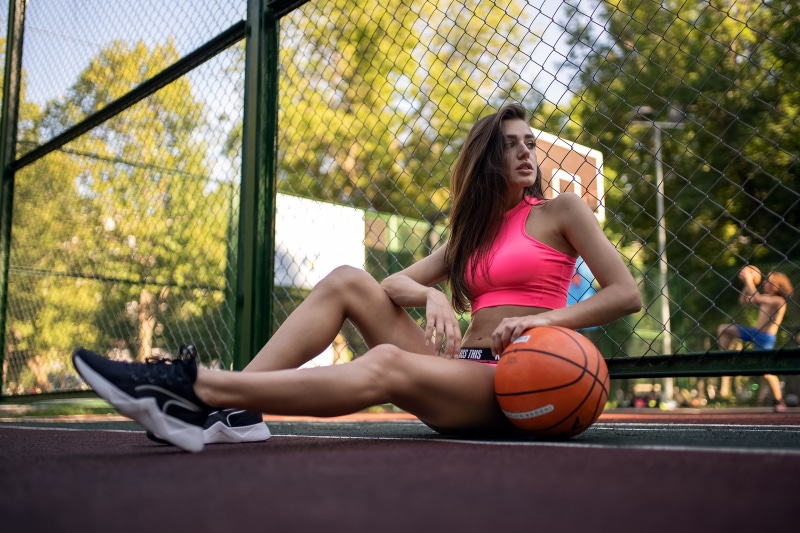 Brunette girl in pink top with basketball on court