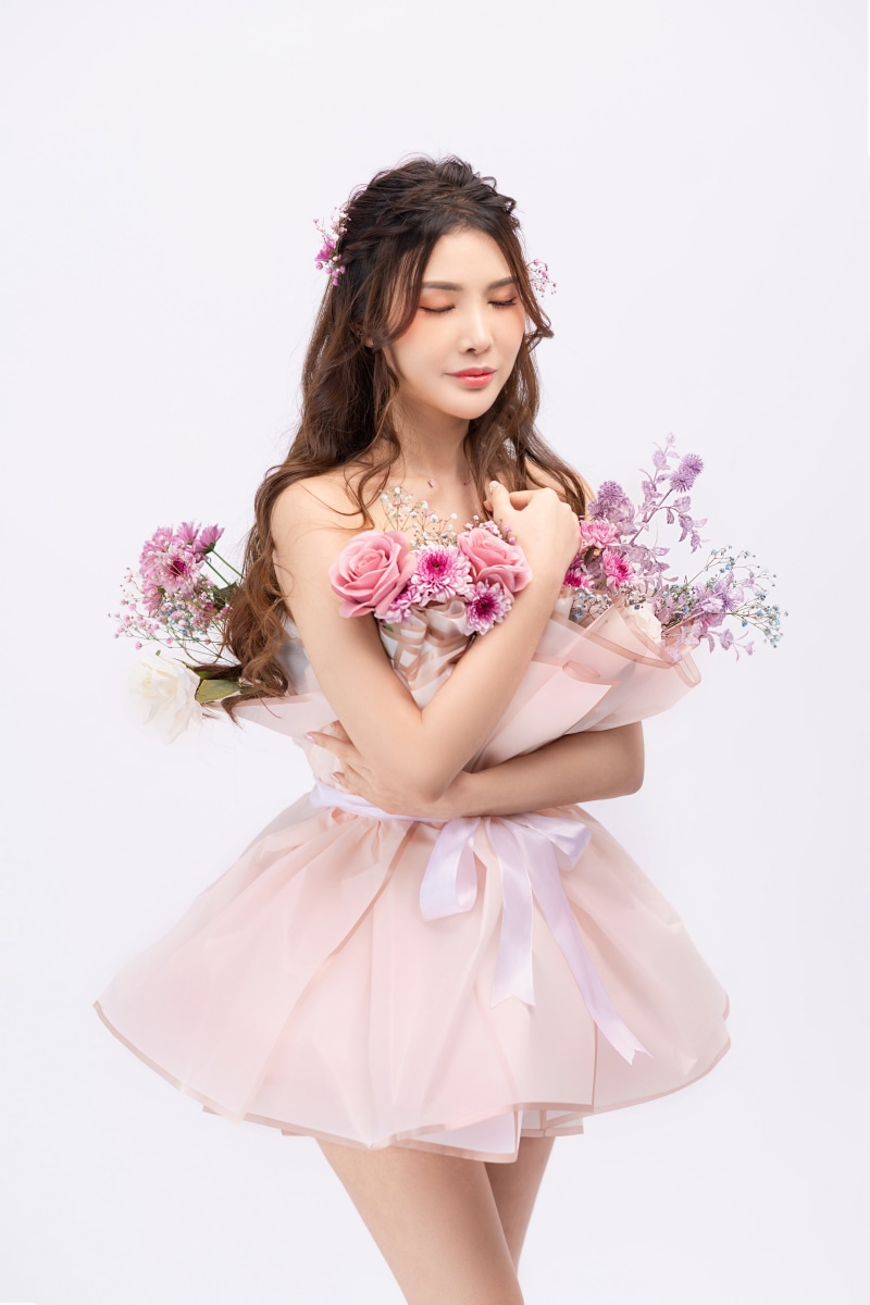 Asian woman in a pink dress holding flowers