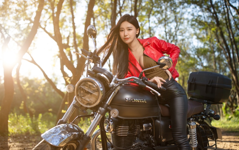 Brunette girl in red jacket on Honda motorcycle
