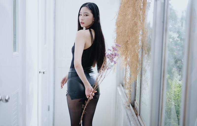 Asian woman in black skirt and pantyhose holding flowers