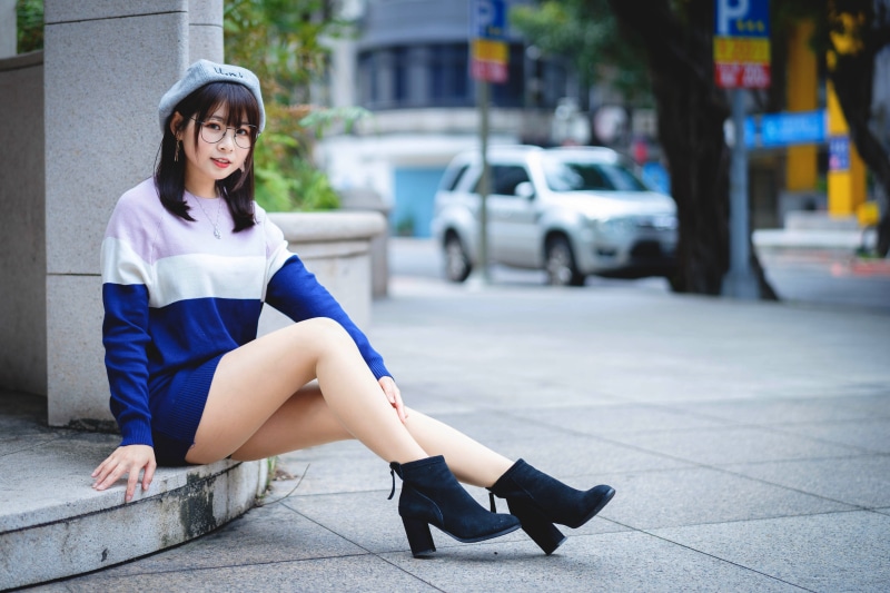 Asian girl wearing beret and glasses sitting outdoors