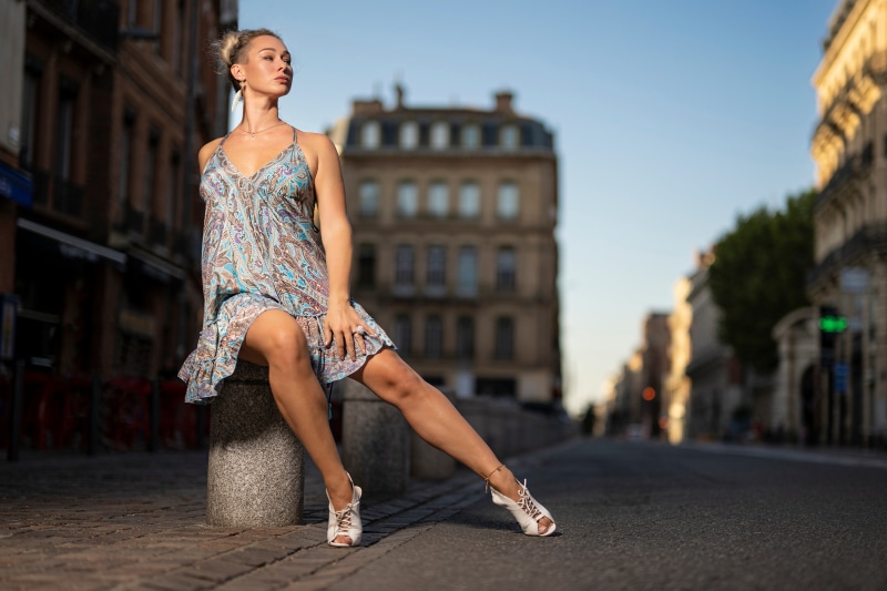 Woman in a patterned dress sitting on a stone bollard