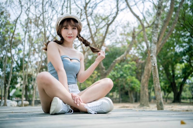 Asian woman in baseball cap and braid hair sitting in lotus position
