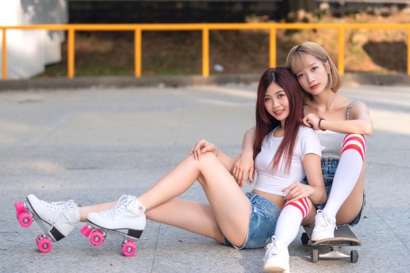 Two Asian women with roller skates and skateboard