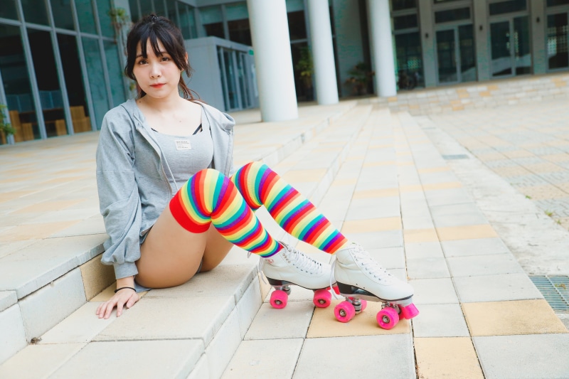 Asian woman sitting with roller skates and rainbow knee-highs