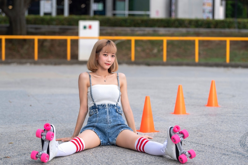 Asian woman in roller skates sitting outdoors