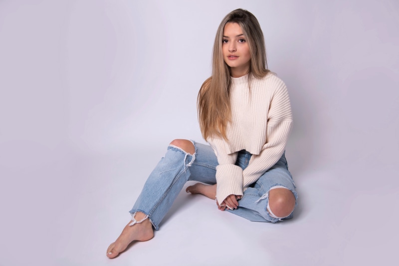 Arianne sitting in ripped jeans and sweater