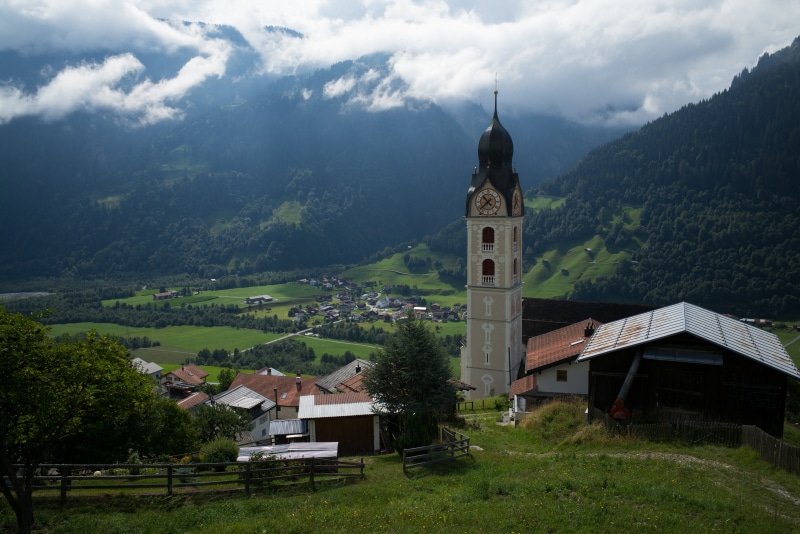 Church tower in Sumvitg, Switzerland with Alps and valley