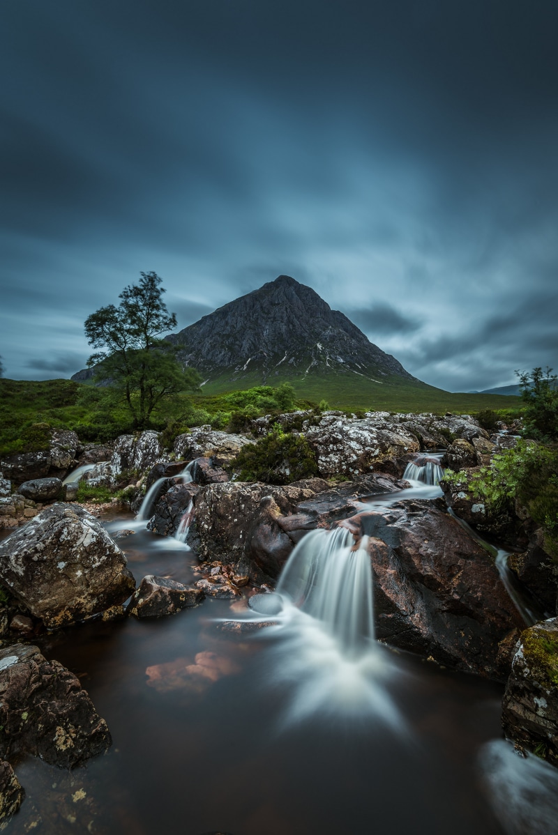 Waterfall flowing over rocks with a mountain in the background