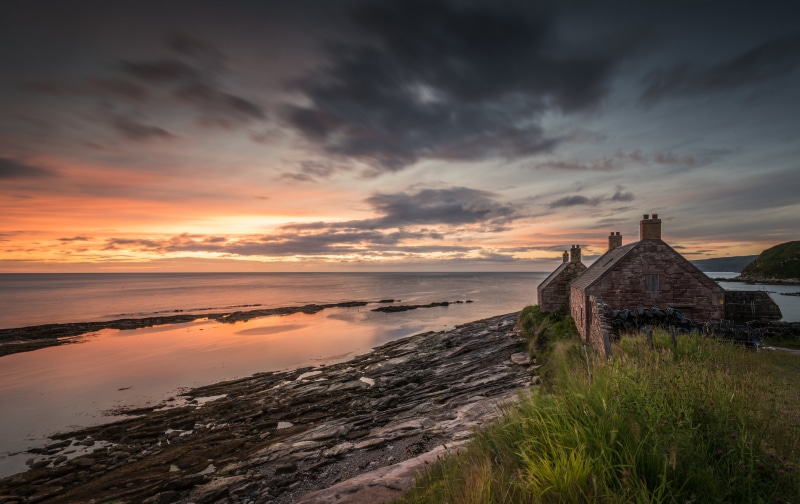 Stone houses on a rocky coast at sunset in Scotland