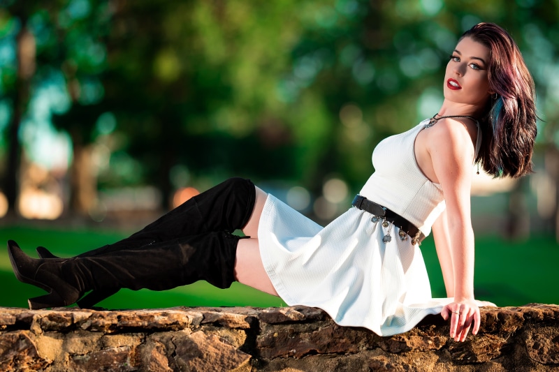 Woman in white dress and black boots posing