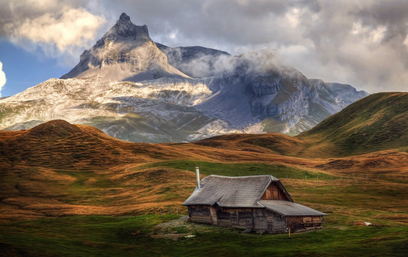 Wooden house in Swiss Alps mountains with clouds