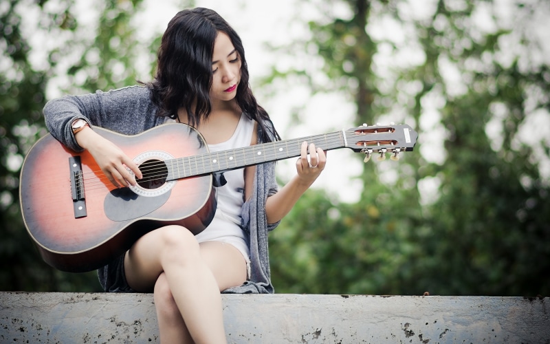 Asian woman playing guitar outdoors