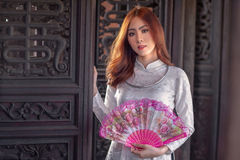 Asian woman with red hair holding a fan