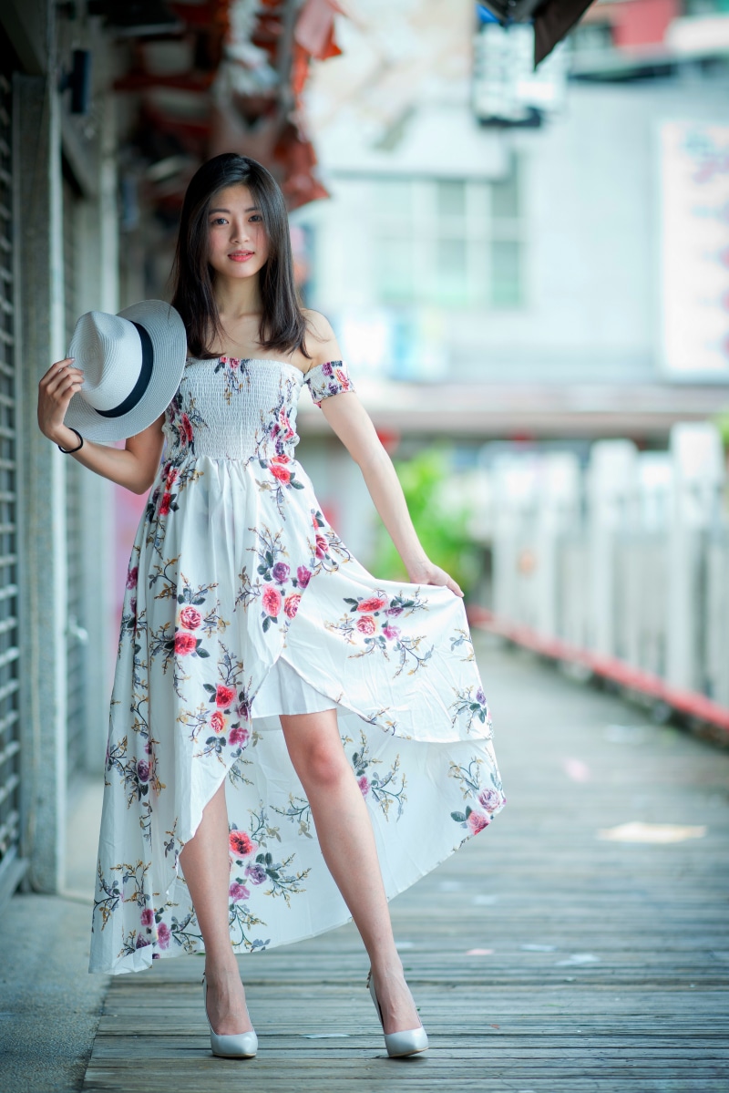 Asian woman in floral dress holding a hat