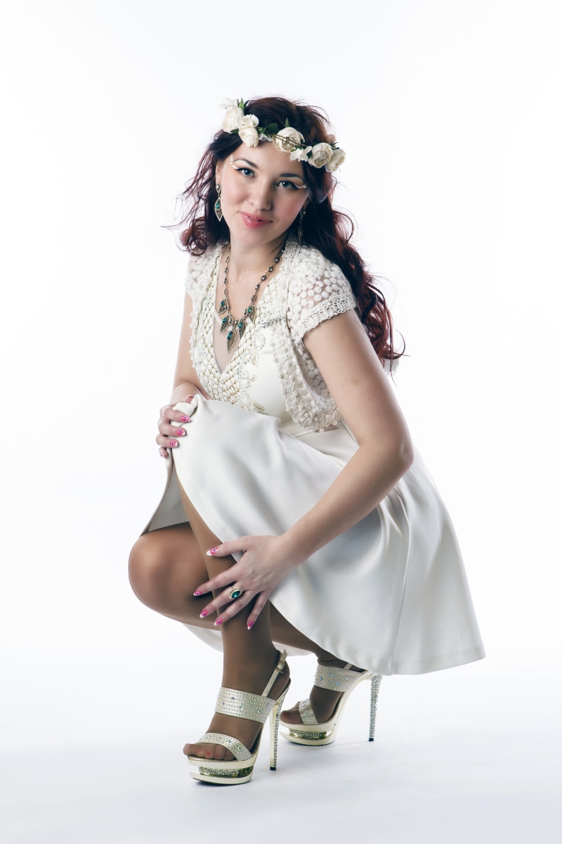 Woman in white dress with flower wreath and stilettos