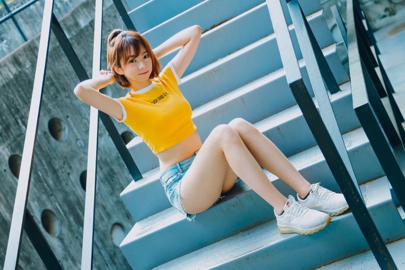Asian girl in shorts and t-shirt sitting on stairs