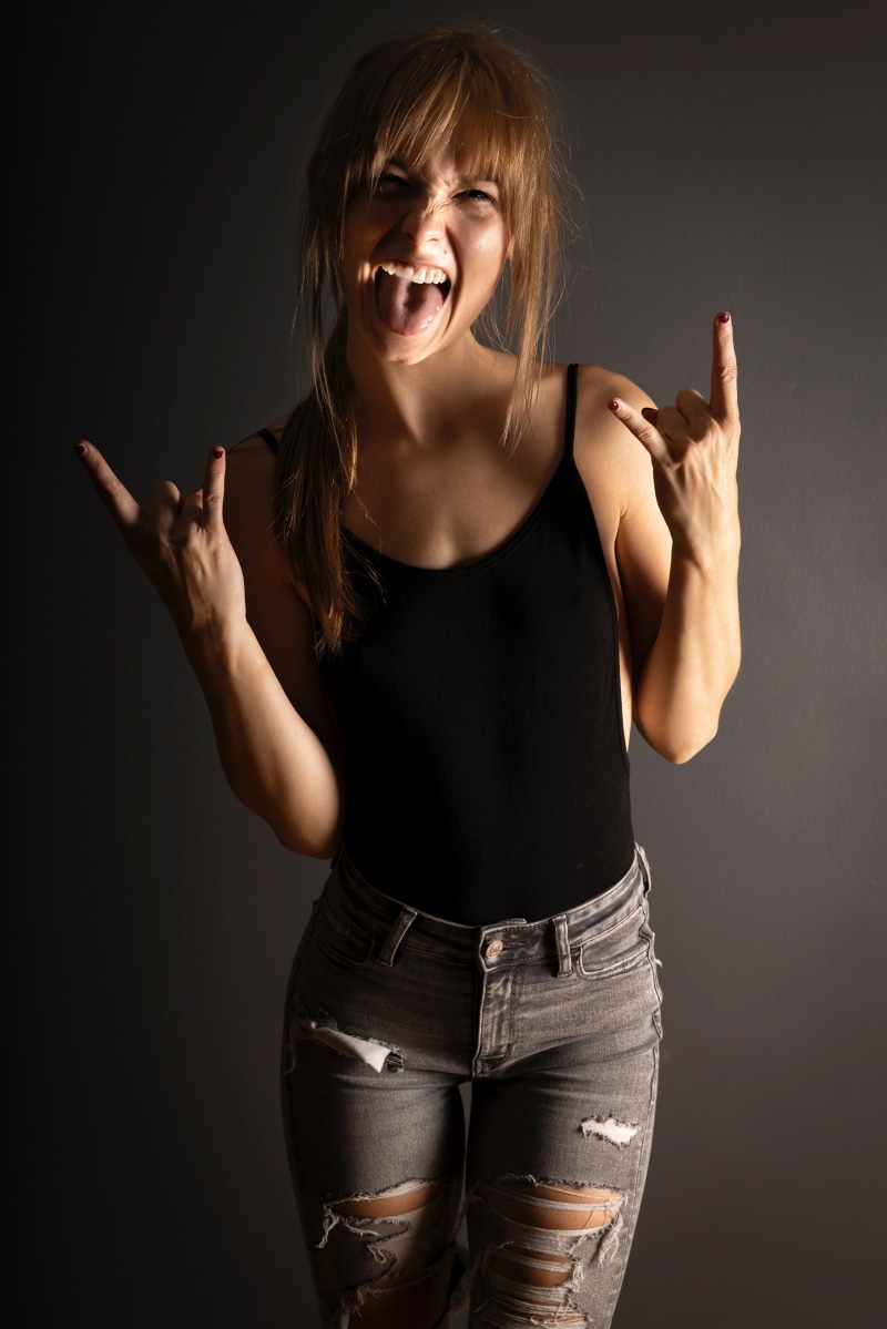 Woman with tongue out and hands in rock on gesture
