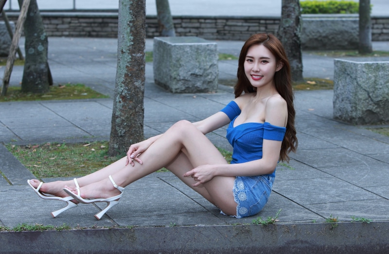 Asian woman with brown hair sitting outdoors