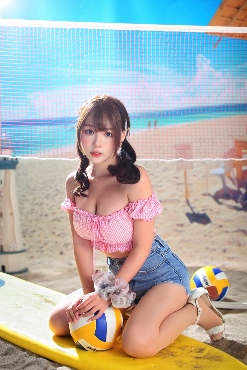 Asian woman in pink blouse and denim shorts on beach
