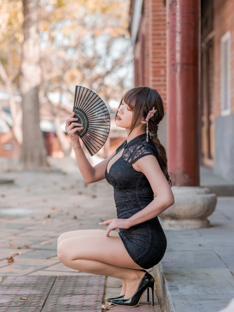 Woman in black dress holding a fan