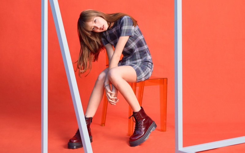 Asian woman in plaid dress and boots sitting on chair