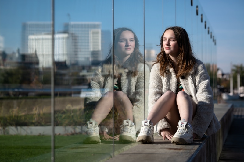 Girl sitting by a glass wall with reflection