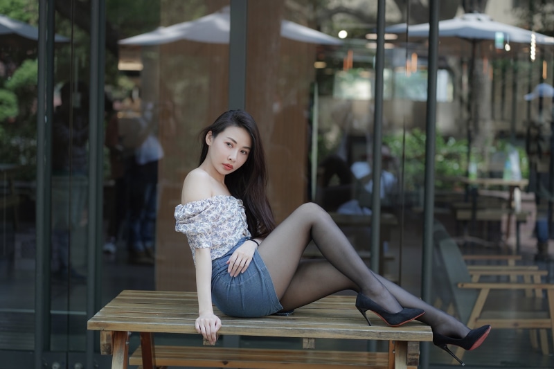 Asian woman sitting on a table wearing pantyhose and stilettos