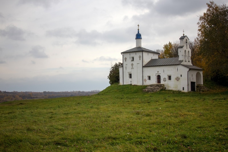White church on a grassy hill in Pskov region, Russia