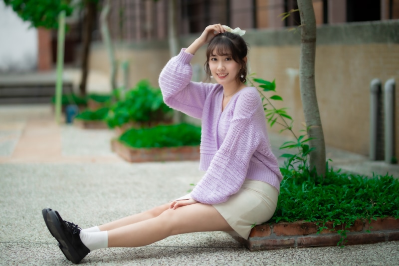 Asian woman sitting outdoors, smiling