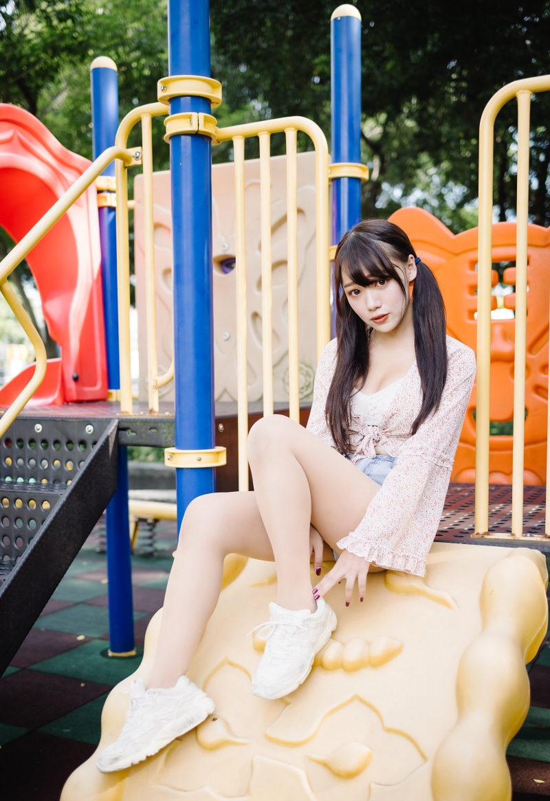 Asian girl with pigtails sitting on a playground slide