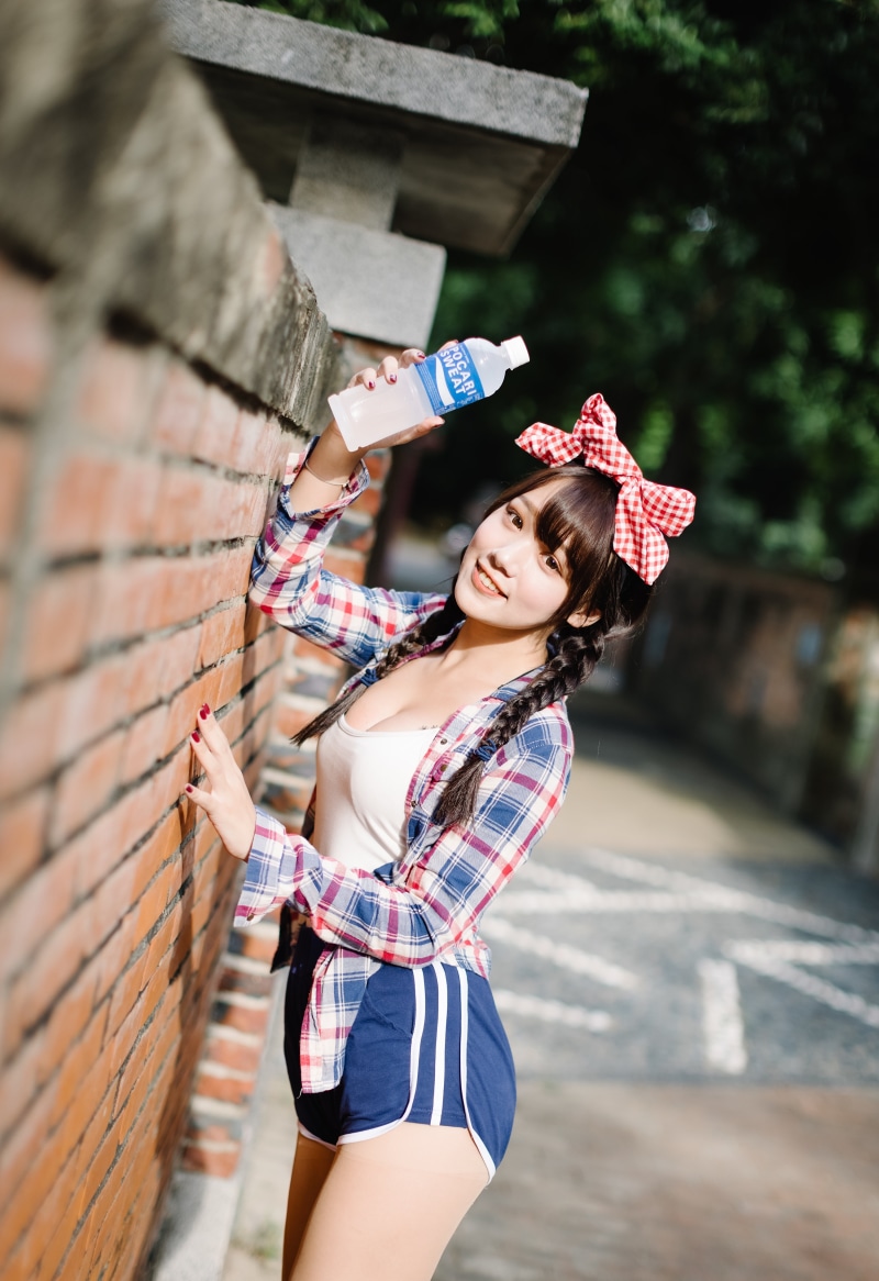 Asian girl with Pocari Sweat bottle near brick wall