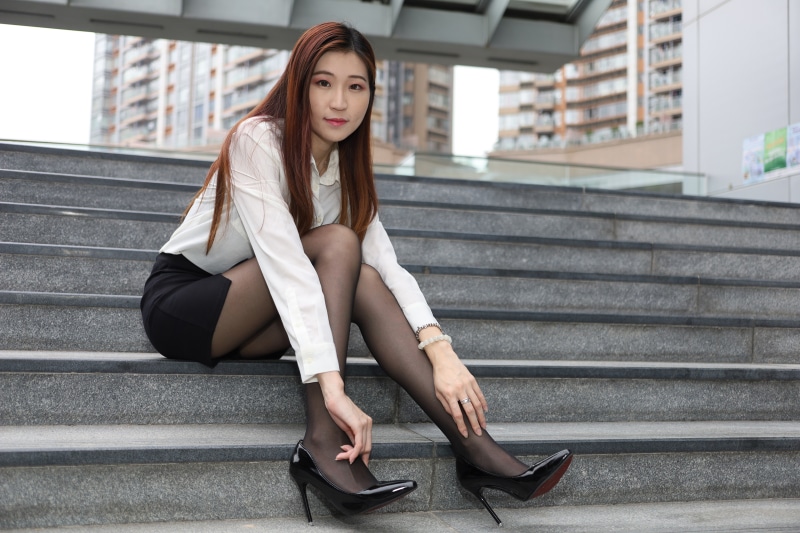 Asian woman in blouse and skirt sitting on stairs