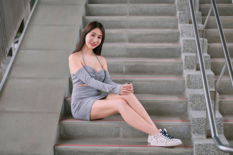 Asian woman with brown hair sitting on stairs